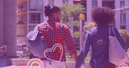 Multiple pink heart icons floating against african american couple holding hands while walking. love and relationship conceptの写真素材