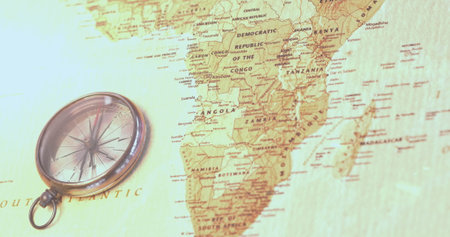 A compass lies on a map focusing on African countries. The map and compass suggest planning for...