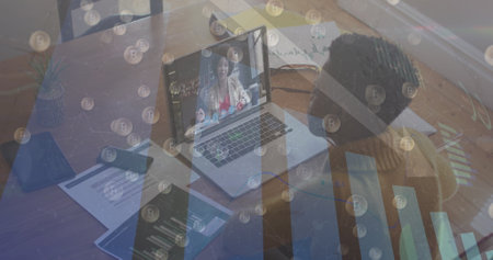 Young African American woman engages in a video call on her laptop. The overlay of financial charts...