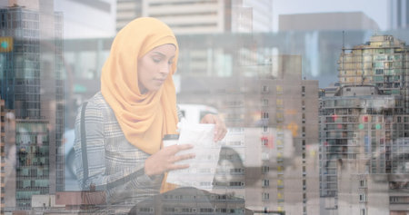 Image of asian woman in hijab sitting and eating over cityscape. out and about in the city,...