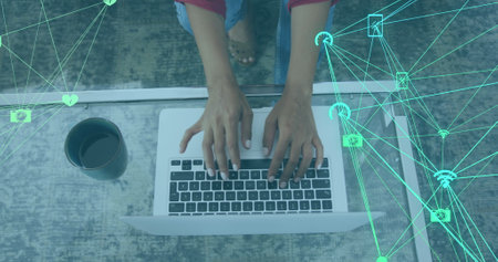 Image of networks of connections with digital icons over woman using laptop at home. global social media and online connection concept digitally generated image.の写真素材