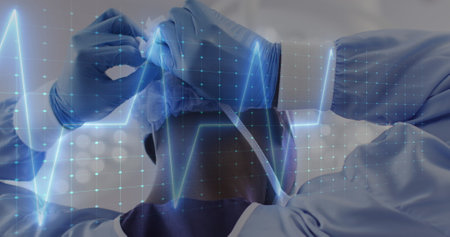 Image of cardiograph over african american male surgeon wearing face mask at hospital. Medicine,...