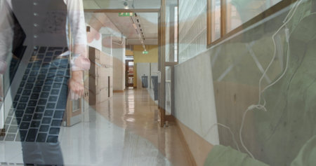 Image of hands of man using laptop with businessman walking in workplace corridor. business and...