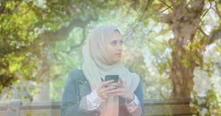 Image of asian woman in hijab using smartphone, over forest. communication technology and keeping in touch, digitally generated image. sianwの写真素材