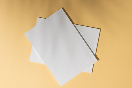 Blank white paper sheets on a beige background, with copy space. Office essentials for writing or printing are neatly arranged, ready for use.の写真素材