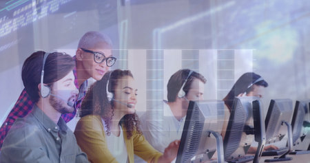 Image of financial graphs and data over diverse female and male call center workers. Business, call center, finance, economy and working with technology concept digitally generated image.の写真素材