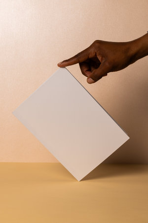 African American hand holding a blank card, with copy space. Ideal for a message or advertisement, the neutral background enhances focus.の写真素材