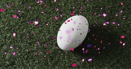 Image of confetti over white rugby ball on grass. Rugby, sports, competition and celebration concept digitally generated image.の写真素材