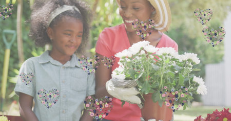 Image of hearts over smiling african american mother and daughter gardening plants. family life, love and nature concept digitally generated image.の写真素材