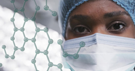 Image of element structure over african american female surgeon in cap and face mask. Surgery, hygiene, data, digital interface, connection, hospital and healthcare, digitally generated image.の写真素材