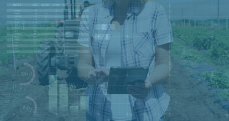 Image of financial data processing over caucasian woman with tablet in field. Global finance, business, connections, computing and data processing concept digitally generated image.の写真素材