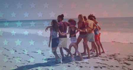Group of young adults walking together on a beach. The overlay of stars adds a dreamy effect to the...