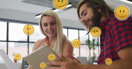 Image of media icons over caucasian business people using tablet. global networks, business, data processing and digital interface concept digitally generated image.の写真素材