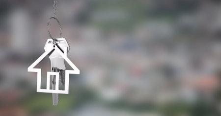 House-shaped keychain with keys over blurred cityscape image. Real estate, urban, lifestyle, property, security, homeの写真素材