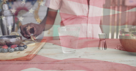 Image of american flag over african american barman preapring cocktails at sunny outdoor bar. America, summer, celebration, free time and vacations, digitally generated image.の写真素材