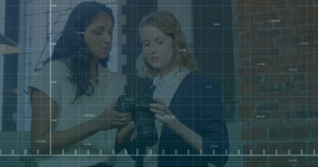 Analyzing camera settings, two women over stock market data image. Business, analysis, technology, finance, teamwork, collaborationの写真素材