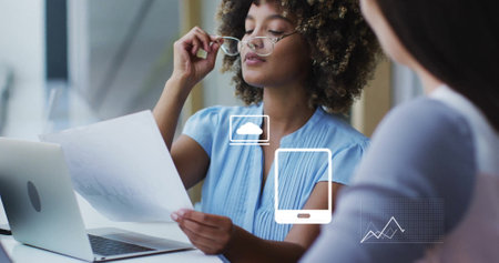 Image of financial data processing with icons over diverse colleagues discussing work in office....