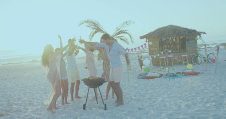 Group of friends enjoying a beach barbecue at sunset. They are toasting with drinks, celebrating in a relaxed, festive outdoor setting.の写真素材