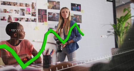 Green financial graph image over diverse team discussing in creative office. Finance, digital, teamwork, collaboration, brainstorming, strategyの写真素材