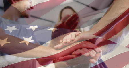 Image of flag of united states of america over caucasian friends stacking hands. american patriotism and friendship concept digitally generated image.の写真素材