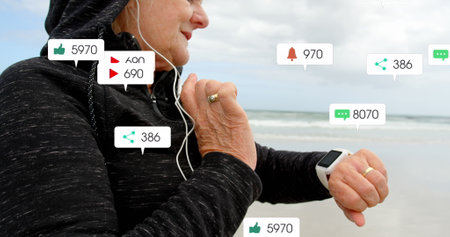 Image of notification bars over senior caucasian woman with headphone using smartwatch at beach....