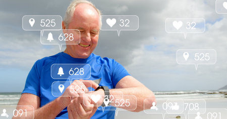 Image of notification bars over senior caucasian man using smartwatch at beach. Digital composite, multiple exposure, social media reminder, retirement and technology concept.の写真素材