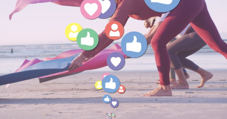 Image of media icons over diverse women with yoga mats at beach. social media and communication interface concept digitally generated image.の写真素材