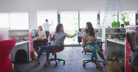 Financial data processing against two african american women discussing over a document at office. Global finance and business technology conceptの写真素材