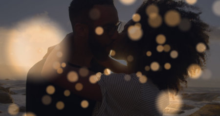 Image of light spots over african american couple at beach. Free time and holidays concept digitally...