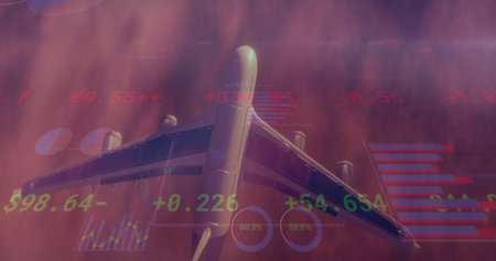 Image of charts and financial data processing over aeroplane flying in cloudy sunset sky. Global finance, business, travel, data and digital interface concept digitally generated image.の写真素材