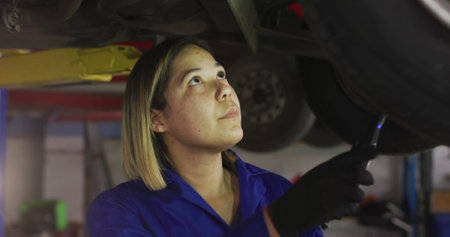 Image of light over biracial female car mechanic checking car. Cars, services, running own small...