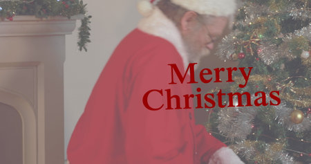 Caucasian senior male wearing Santa Claus costume decorating Christmas tree. He has white hair and beard, looking focused on taskの写真素材