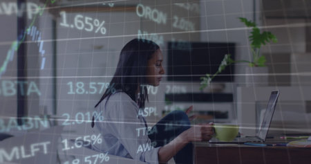Image of and financial stock market data processing over biracial woman using laptop at home. Global economy and business technology conceptの写真素材