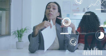 Image of data processing over biracial businesswoman in office. Global business and digital interface concept, digitally generated image.の写真素材