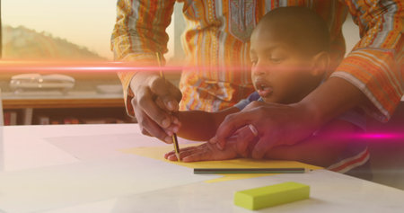 Image of light flashing over african american father and son drawing hand on paper. Family,...