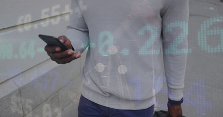 An african american man is out and about in the city, walking down the street and using his smartphone.の写真素材