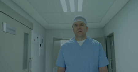 A middle-aged Caucasian male, doctor, standing in a hallway. He has short, light-colored hair and is...