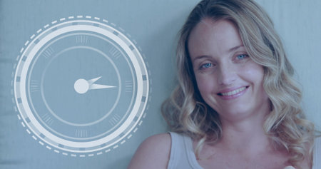 Caucasian fitness class participant smiling, standing near digital clock display. She has light brown hair, blue eyes, and is wearing a simple tank topの写真素材