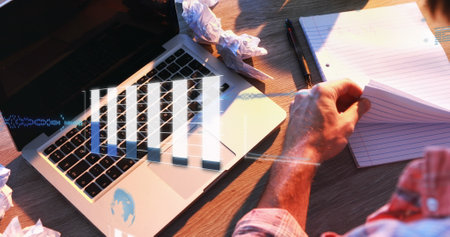 Image of graphs, computer language and globes, overhead view of biracial man working on laptop....