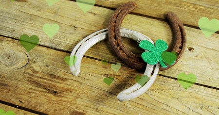 Image of st patrick's shamrock, horseshoe and green hearts on wooden background. St patrick's day, irish tradition and celebration concept digitally generated image.の写真素材