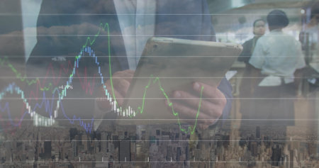 Image of financial data and graphs over caucasian businessman using tablet. Global communication, finance and technology concept digitally generated image.の写真素材