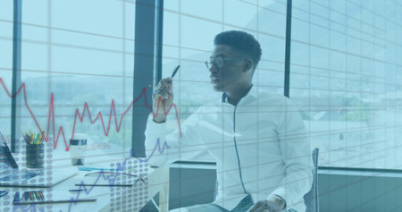 Image of financial graphs and data over african american man in office. Business, finance and economy concept digitally generated image.の写真素材