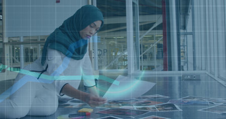 Image of financial data processing over biracial businesswoman working at office. Global business, finances and digital interface concept, digitally generated image.の写真素材