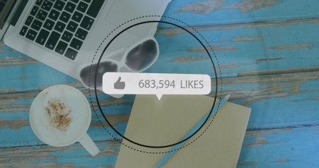 Image of like icon with increasing numbers over coffe cup, diary, laptop on wooden surface. Computer interface and business data technology conceptの写真素材