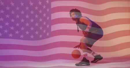 Image of american flag over african american male basketball player bouncing ball. Sport, competition, confidence, skill, flag, game, nationality and patriotism digitally generated image.の写真素材