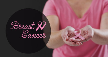 Image of breast cancer text over caucasian woman with pink ribbon on black background. Breast cancer awareness concept digitally generated image.の写真素材