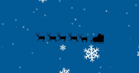 Image of santa claus in sleigh with reindeer over snow falling on blue background. Christmas, tradition, celebration and festivity concept digitally generated image.の写真素材