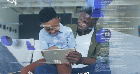 Image of data processing over african american father and son using tablet. Global business and digital interface concept digitally generated image.の写真素材