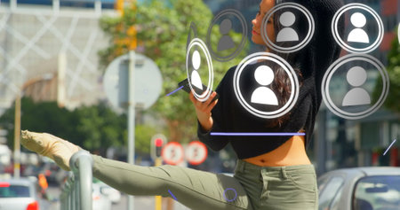 Image of media icons and shapes over biracial businesswoman using smartphone. global business and digital interface concept digitally generated image.の写真素材