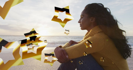 Image of stars over biracial woman at beach. Christmas, celebration and digital interface concept...